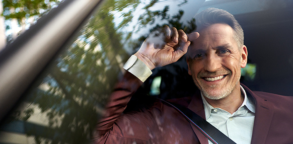 Ein lächelnder Mann sitzt in einem BMW auf Beifahrersitz und schaut aus dem Fenster