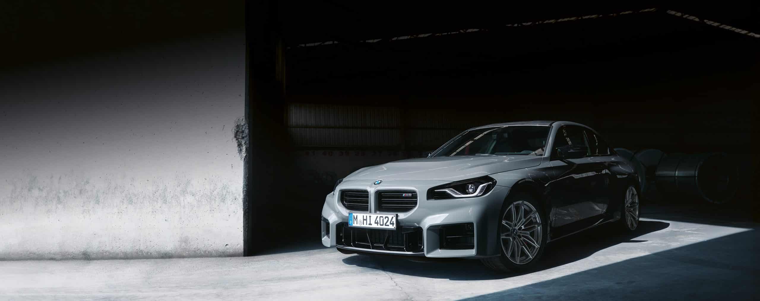 Graues BMW 2er Coupé M Automobil parkend in einer Garage, Fokus auf die Front, besonders den rechten Scheinwerfer und den Kühler