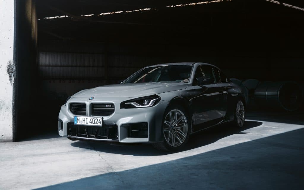 Graues BMW 2er Coupé M Automobil parkend in einer Garage, Fokus auf die Front, besonders den rechten Scheinwerfer und den Kühler