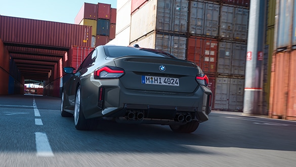 Heckansicht eines dunkelgrauen BMW 2er Coupé M Automobils in Bewegung in einem Industriegebiet