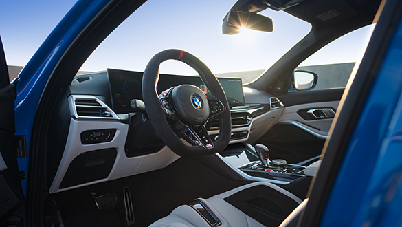 Blick über die Fahrerseite ins Cockpit des BMW 3er Competition Touring M Automobils, sportliches Lenkrad und BMW Curved Display