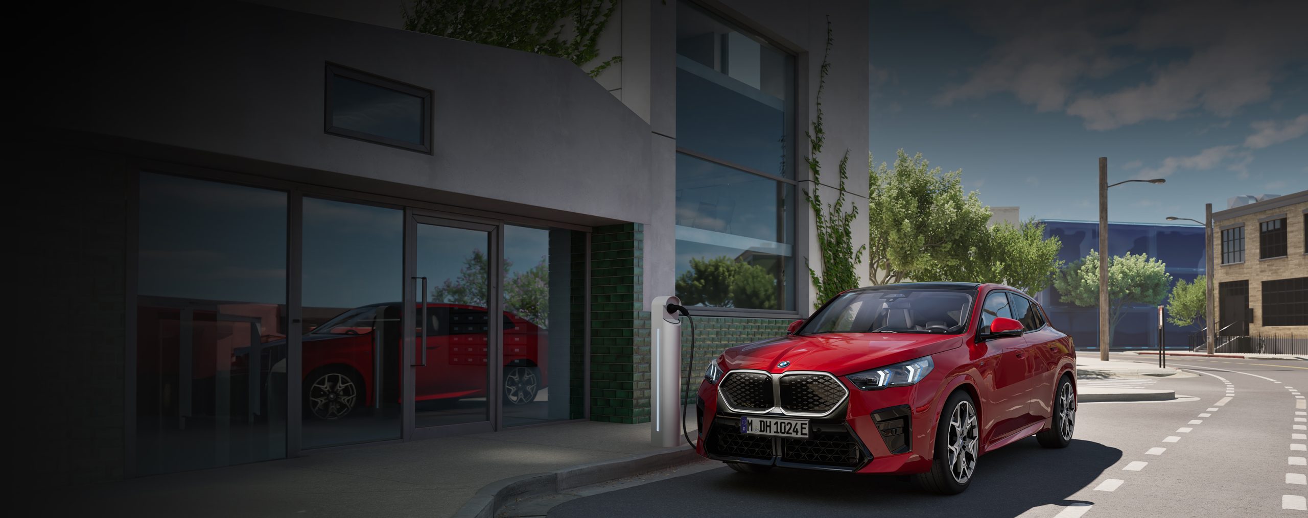 Roter BMW iX2 parkt an öffentliche Elektro-Ladesäule an der Straße, in urbaner Umgebung