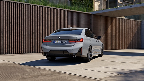 Heckansicht einer grauen BMW 3er Limousine vor einer holzverkleideten Wand