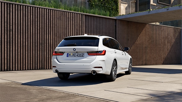 Heckansicht eines weißen BMW 3er Touring vor einer holzverkleideten Wand