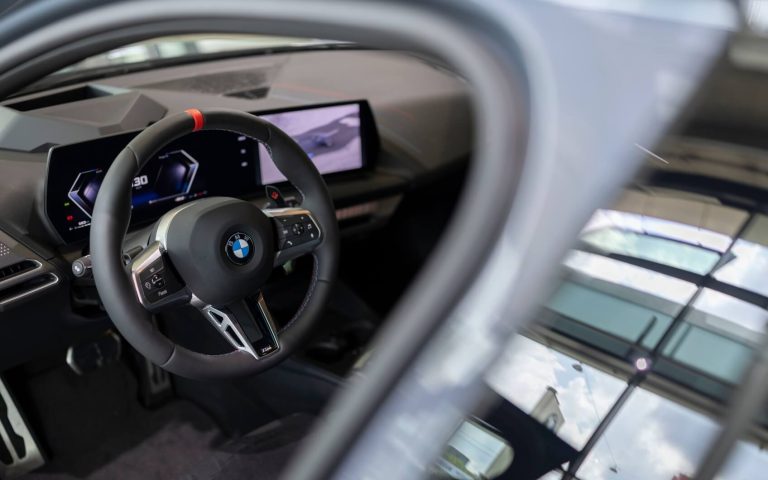 Blick auf die Fahrerseite des BMW M135, Fokus auf dem Sportlenkrad und BMW Curved Display