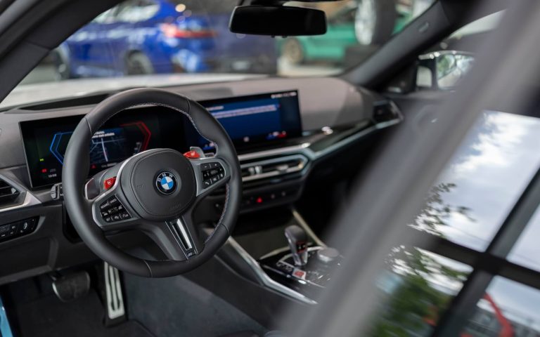 Blick auf die Fahrerseite des BMW M2 Coupés, Fokus auf dem Sportlenkrad und BMW Curved Display