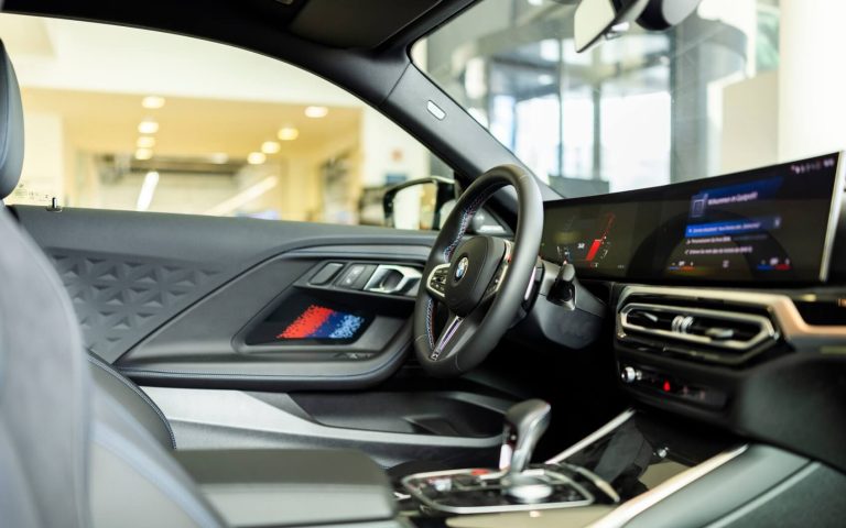 Cockpit eines BMW M2 Coupé im Malboro Design aus der Perspektive des Beifahrers mit Fokus auf das BMW Lenkrad und die Bedienelemente im Showroom der Automag