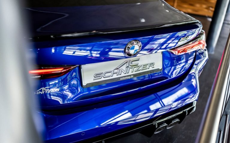 Heckansicht eines BMW M4 Competition Coupé, getunt von AC Schnitzer, in der Farbe Dunkelblau mit Fokus auf die Heckleuchten, aufgenommen im Showroom der Automag