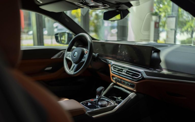 Cockpit eines BMW M4 Competition Coupé aus der Perspektive des Beifahrers mit Fokus auf das BMW Lenkrad und das Display, aufgenommen im Showroom der Automag