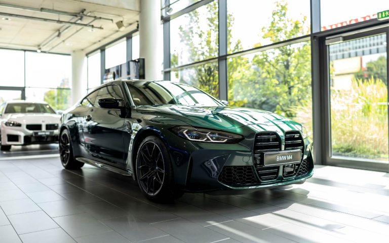 Frontaufnahme eines BMW M4 Competition Coupé in der Farbe Grün mit Fokus auf die rechte Front, aufgenommen im Showroom der Automag