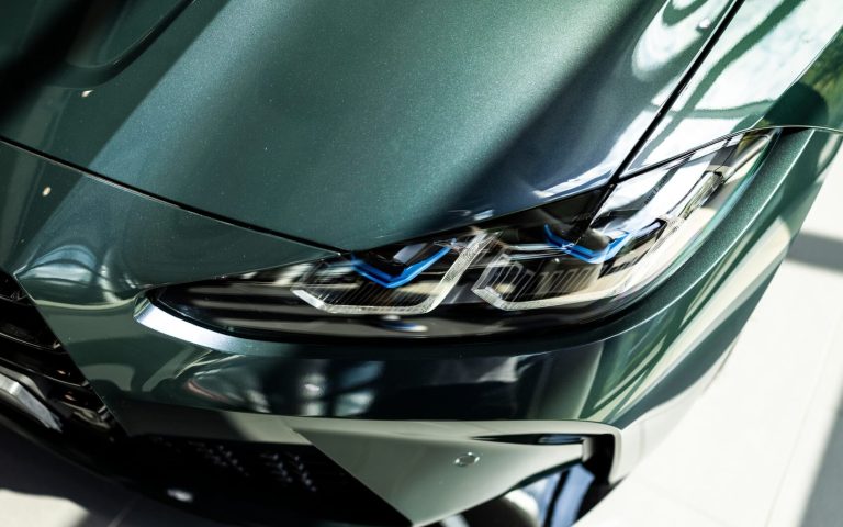 Detailaufnahme des linken Frontscheinwerfers eines BMW M4 Competition Coupé in der Farbe Grün, aufgenommen im Showroom der Automag