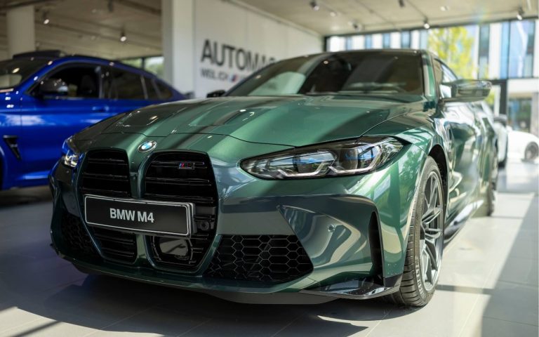 Frontaufnahme eines BMW M4 Competition Coupé in der Farbe Grün mit Fokus auf die linke Front, aufgenommen im Showroom der Automag