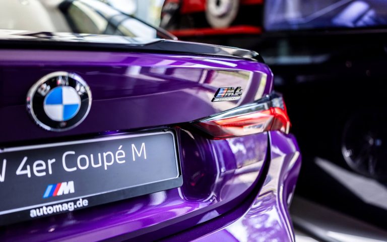 Detailansicht der rechten Heckleuchte eines BMW M4 Competition Coupé in der Farbe Violett, aufgenommen im Showroom der Automag