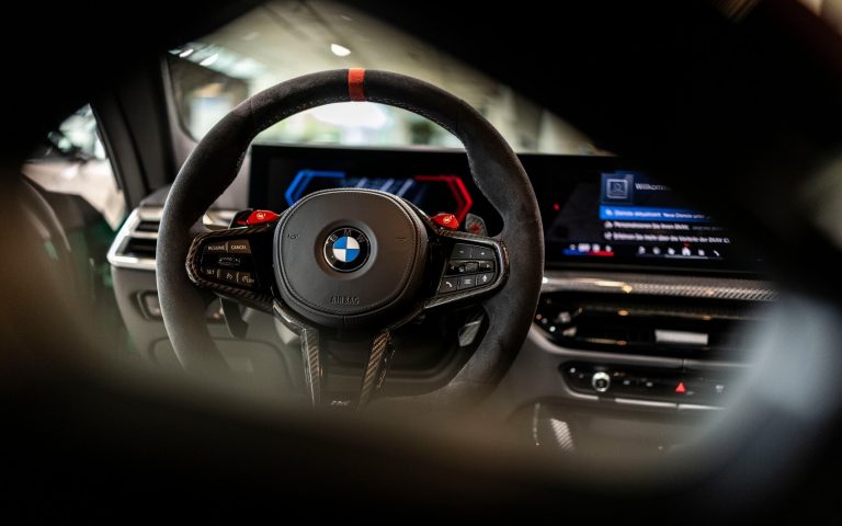 Detailaufnahme des BMW M Lederlenkrades in einem BMW M4 Coupé, fotografiert von der Rückbank im Showroom der Automag