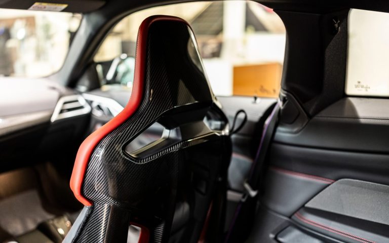 Detailaufnahme des BMW M Sportsitzes auf der Beifahrerseite in einem BMW M4 Coupé, aufgenommen von der Rückbank im Showroom der Automag