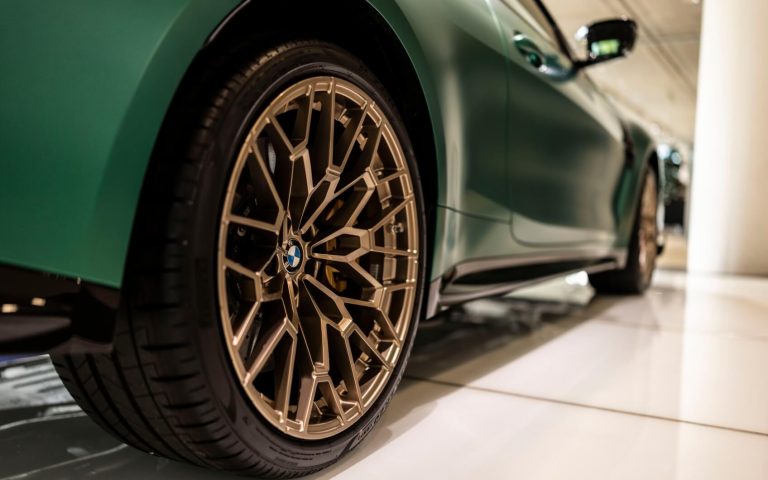 Detailaufnahme des rechten Hinterreifens eines BMW M4 Coupé mit Felgen aus Bronze, aufgenommen im Showroom der Automag