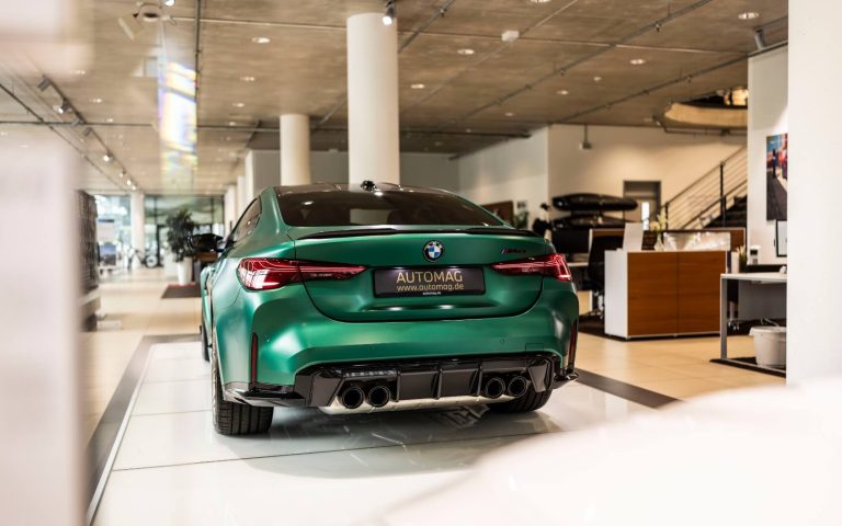 Heckansicht eines BMW M4 Coupé in der Farbe Grün, aufgenommen im Showroom der Automag