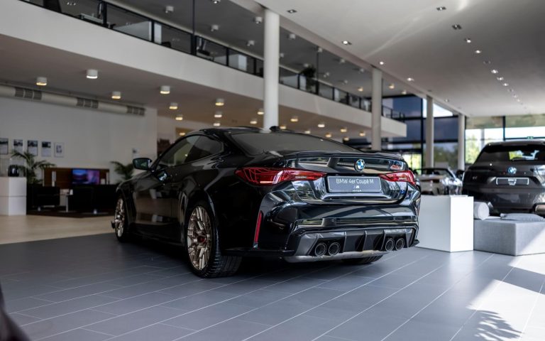 Heckansicht eines BMW M4 Coupé mit Fokus auf die Heckleuchten und den linken Hinterreifen mit Felgen aus Bronze, aufgenommen im Showroom der Automag