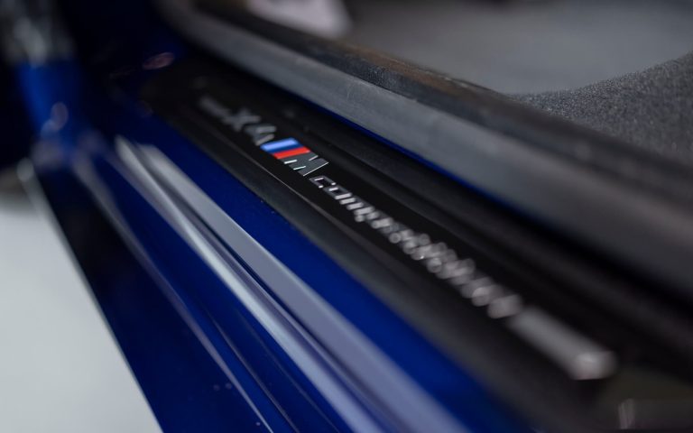 Detailaufnahme der Einstiegsleiste eines BMW X4 M Competition mit BMW M Schriftzug, aufgenommen im Showroom der Automag