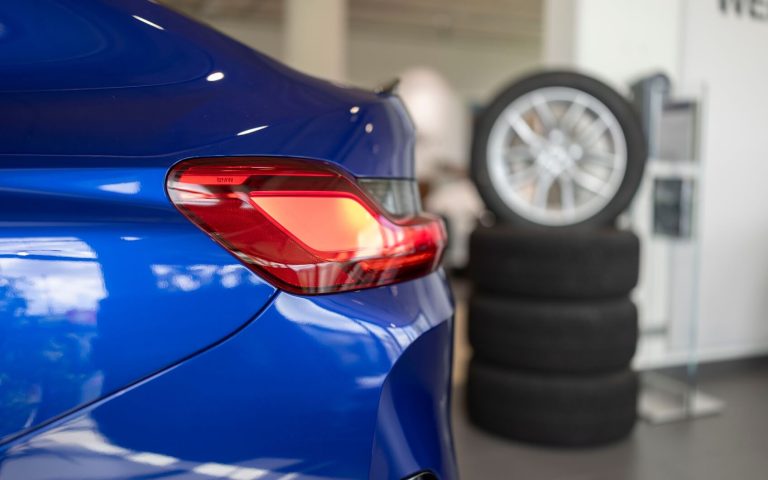 Detailaufnahme der linken Heckleuchte eines BMW X4 M Competition in der Farbe Dunkelblau, aufgenommen im Showroom der Automag