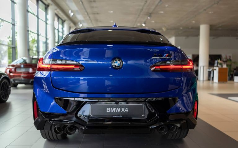 Heckansicht eines BMW X4 M Competition in der Farbe Dunkelblau, aufgenommen im Showroom der Automag