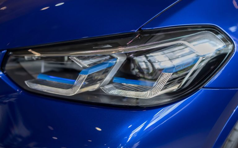 Detailaufnahme des linken Frontscheinwerfers eines BMW X4 M Competition in der Farbe Dunkelblau, aufgenommen im Showroom der Automag