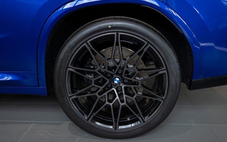 Detailaufnahme des linken Hinterreifens eines BMW X4 M Competititon in der Farbe Dunkelblau, aufgenommen im Showroom der Automag