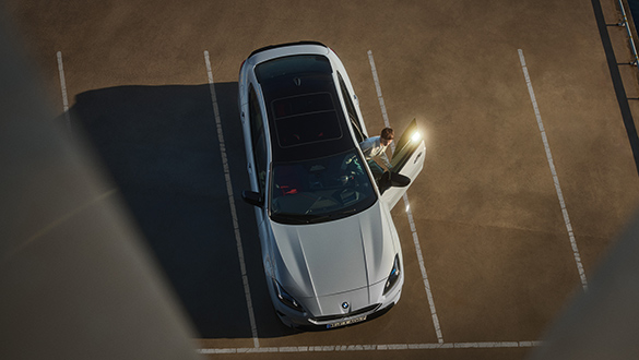 Blick von oben auf ein geparktes BMW 2er Gran Coupé in der Farbe Grau mit geöffneter Fahrertür auf einem Parkplatz
