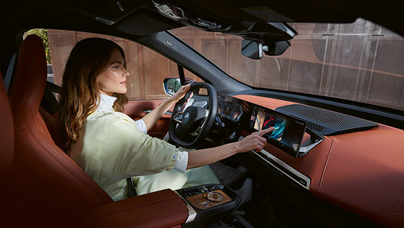 Frau in gelber Bluse bedient Touchscreen des BMW Curved Display im BMW iX