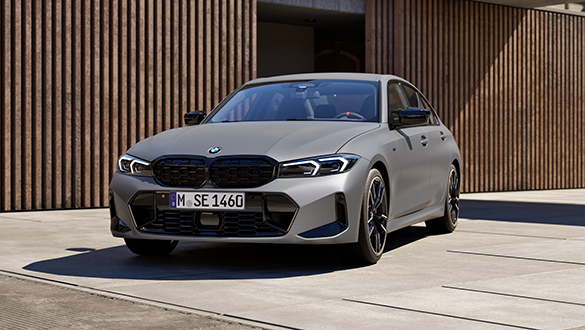 Graue BMW M340i Limousine parkt vor einem modernen urbanen Gebäude, Fokus auf Frontansicht