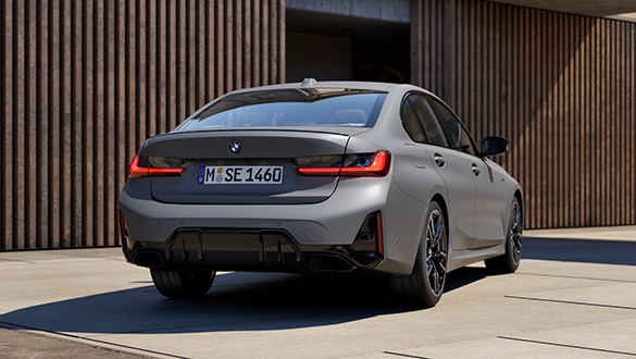 Graue BMW M340i Limousine parkt vor einem modernen urbanen Gebäude, Fokus auf Heckansicht