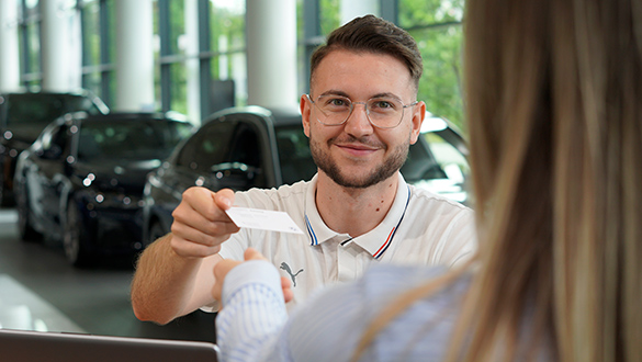 BMW Product Genius im Verkaufsraum, Blick über Schulter einer Kundin