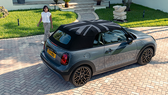 Graues MINI Cooper Cabrio in der Einfahrt eines Wohnhauses mit geschlossenem Sofftop-Verdeck mit Union Jack Motiv