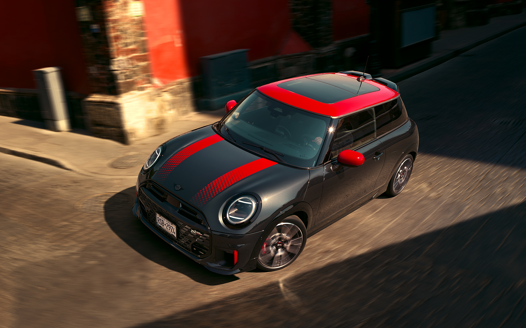 MINI John Cooper Works in der Farbe Schwarz mit roten Sport Stripes in Fahrt an einer Kreuzung