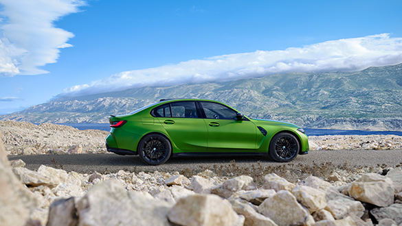Seitenansicht eines grünen BMW 3er Limousine M Automobils auf Schotterstraße, Berglandschaft im Hintergrund
