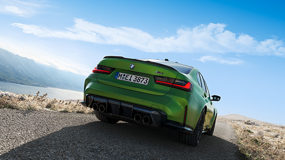Heckansicht auf grüne BMW 3er Limousine M Automobil an einer Küstenstraße mit Berglandschaft im Hintergrund