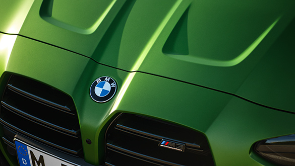 Detailansicht auf markante Front und Motorhaube einer grünen BMW 3er Limousine M Automobil mit Fokus auf das BMW Logo