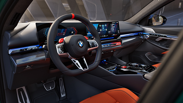 Blick durch die Fahrerseite ins Cockpit des BMW M5 Touring mit BMW M Lederlenkrad und BMW Curved Display
