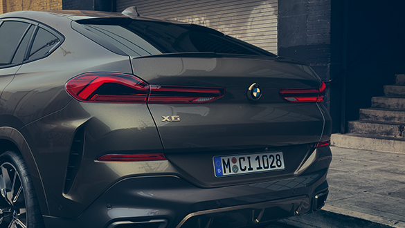 BMW X6 Heckansicht in dunkler Lackierung, parkend in urbanem Umfeld, mit beleuchteten Rückleuchten und Münchner Kennzeichen