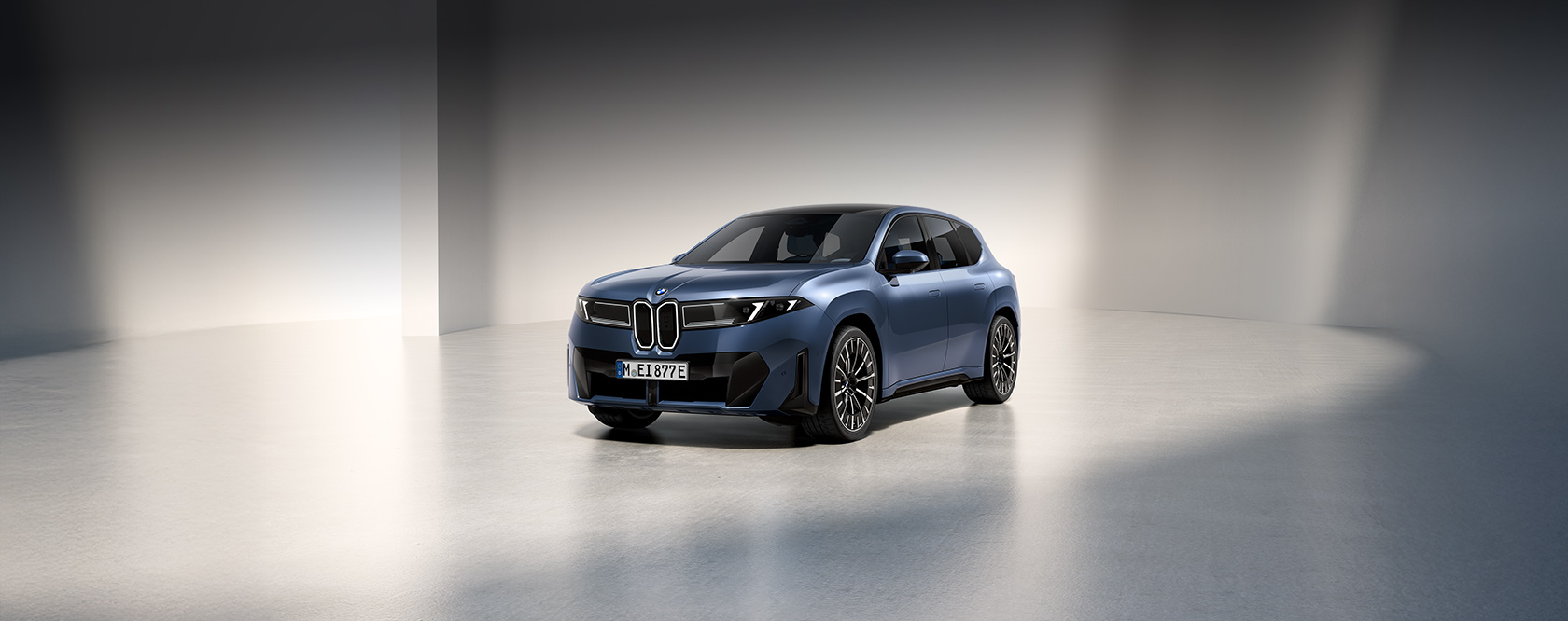 Blauer BMW iX3 in dunkler Studio-Umgebung, frontal seitlich beleuchtet.
