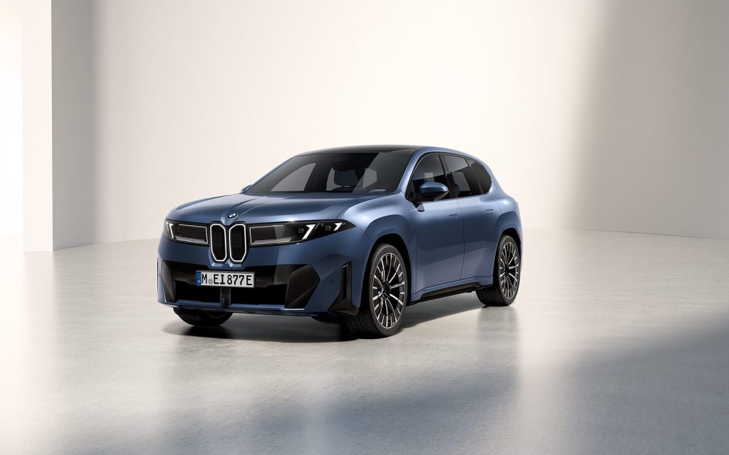 Blauer BMW iX mit schwarzem Dach in heller Studio-Umgebung, Frontansicht leicht seitlich.