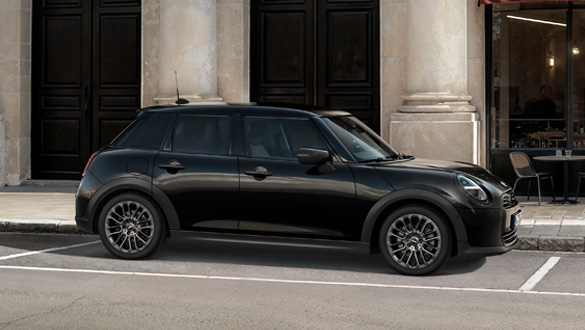 Seitenansicht eines schwarzen MINI Cooper 5-Türers vor einem Gebäude mit Säulen und dunklen Türen.