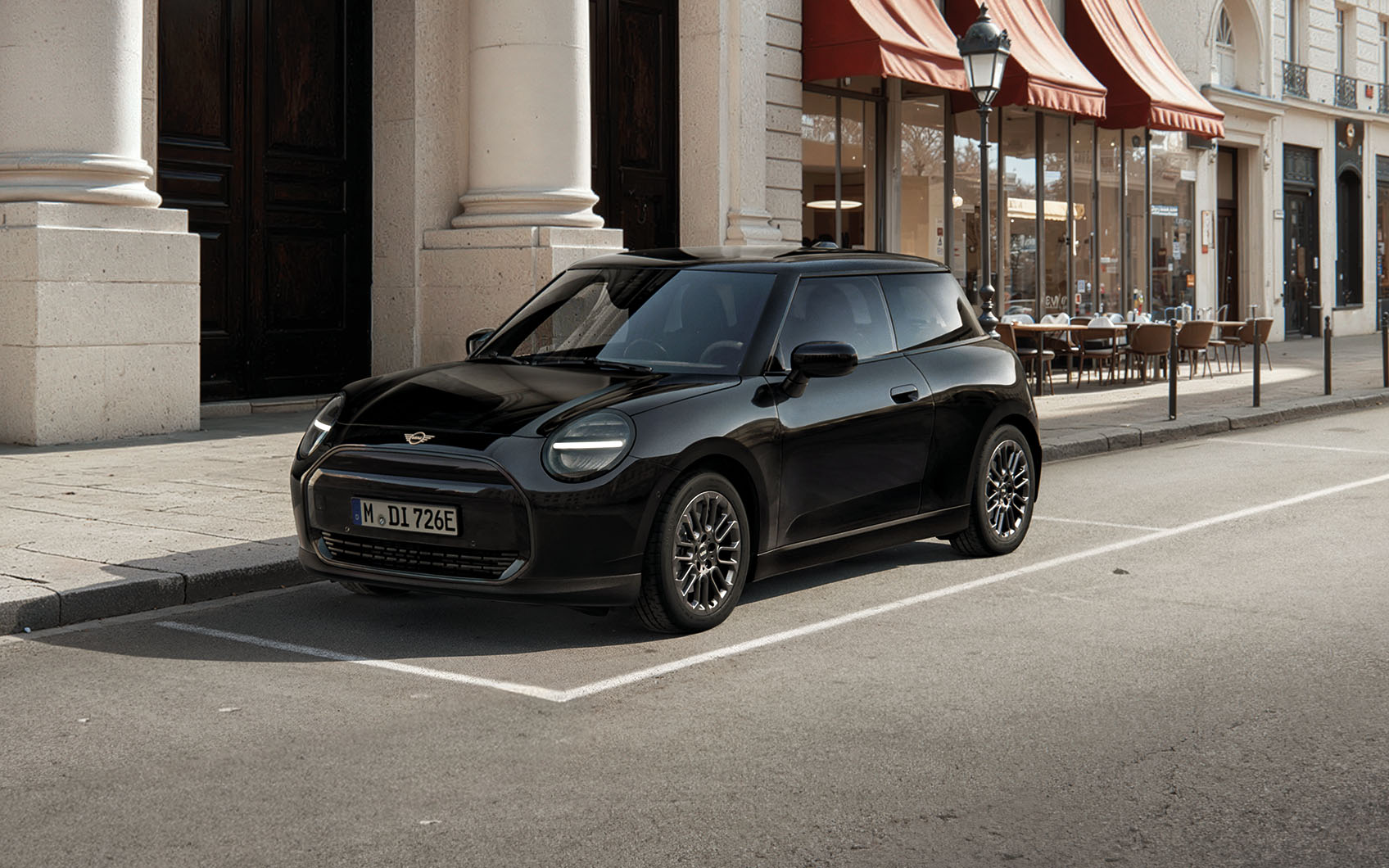 MINI Cooper Electric Blackyard parkt vor Café mit roten Markisen in der Stadt.