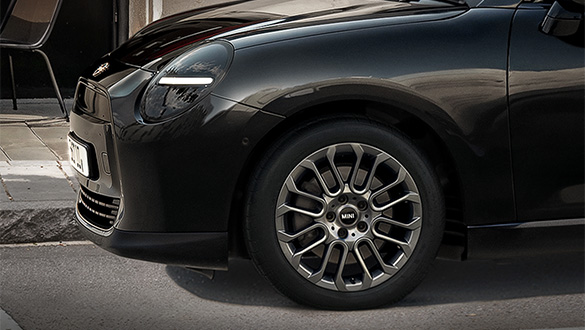 Detailansicht eines schwarzen MINI Coopers mit Fokus auf die Reifen.