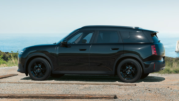 Seitenansicht eines MINI Countryman Blackyard auf einem Küstenweg mit Meer im Hintergrund