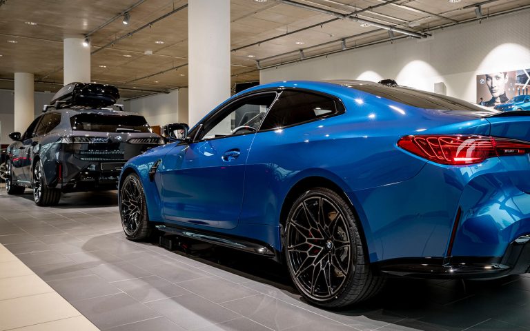 Blauer BMW M4 im Autohaus, Heckansicht schräg von links