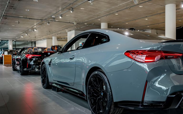 Grauer BMW M4 im Autohaus, Heckansicht schräg