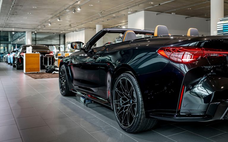 Schwarzes BMW M4 Cabrio im Autohaus, Heckansicht schräg von links