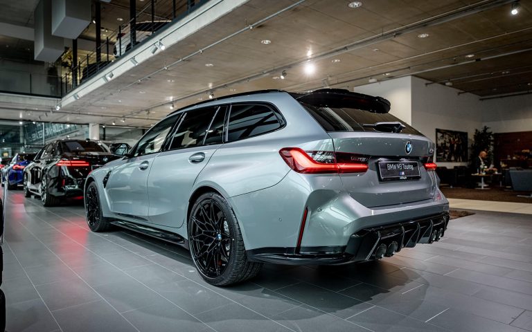 Grauer BMW M3 Touring im Autohaus, Heckansicht schräg von links