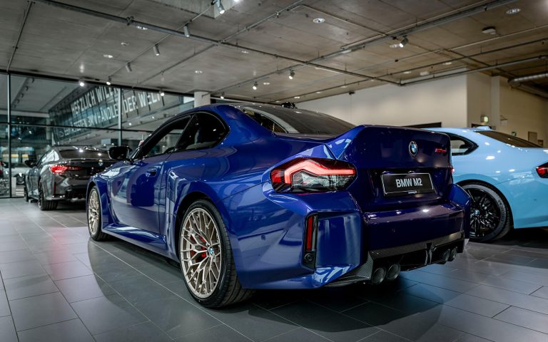 Blauer BMW M2 CS im Autohaus, Heckansicht schräg von links